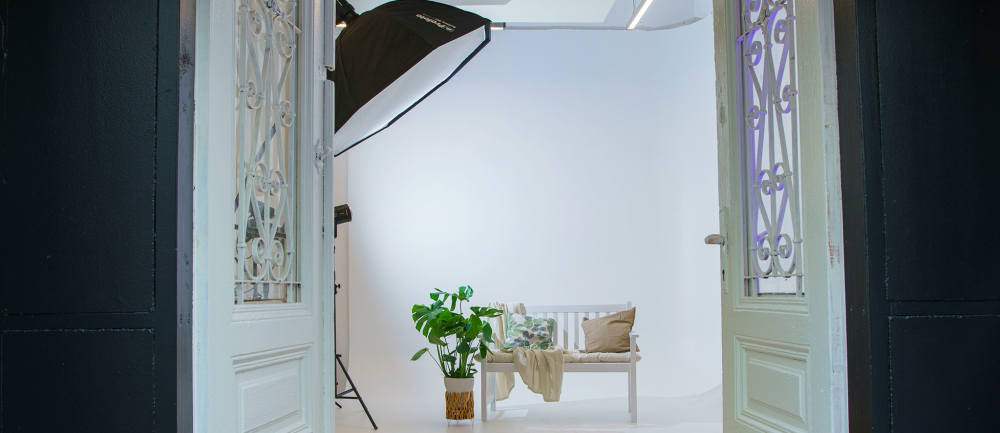 Blick in ein Fotostudio in Wien mit weißer Hohlkehle, Softbox und Sitzbereich.