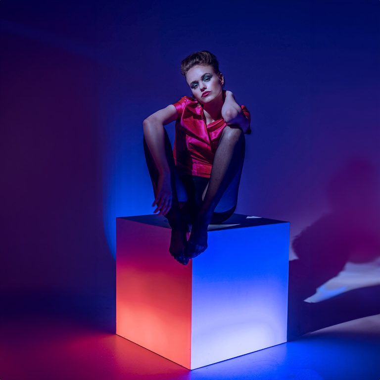 Model sitzt auf leuchtendem Würfel im Studio Wien